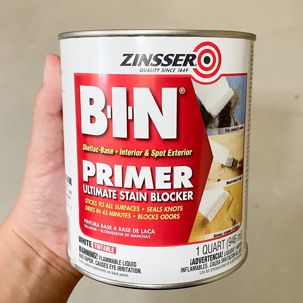 Hand holding a can of Zinsser B-I-N Primer Ultimate Stain Blocker