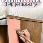A hand painting a wooden dresser pink with a brush; text reads Best Types of Furniture Paint For Beginners.