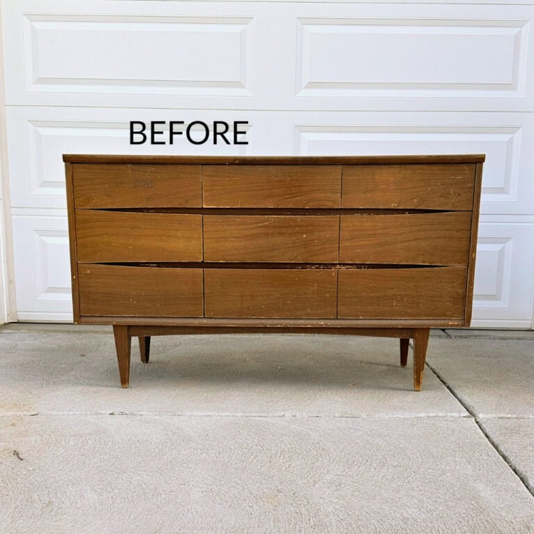 A worn wooden dresser labeled BEFORE, standing on a driveway in front of a white garage door.