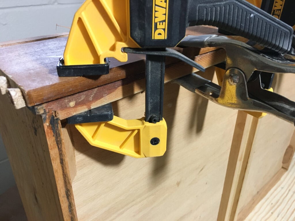 Two clamps securing the corner of a wooden drawer for lifting veneer repair