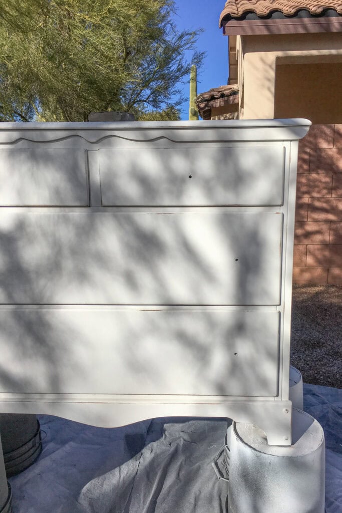 A dresser on top of buckets being painted outdoors