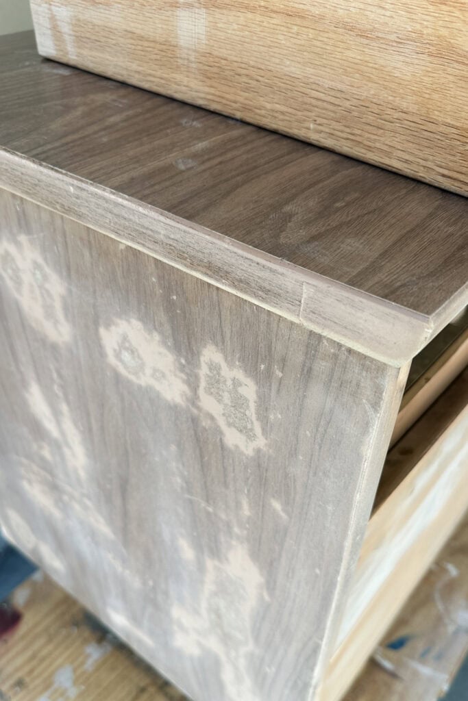 A wooden dresser being sanded, with patches and an open drawer, ready for refinishing.