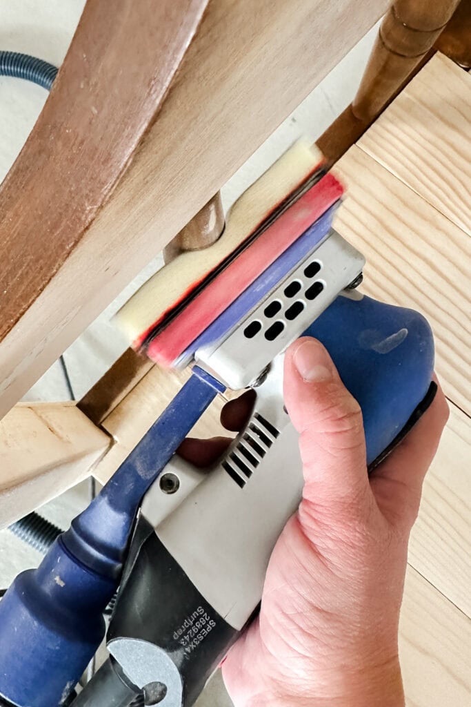 Using electric sander to smooth the spindle of wooden furniture