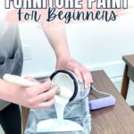 Person pouring white paint from a can into a paint tray, preparing to paint furniture.