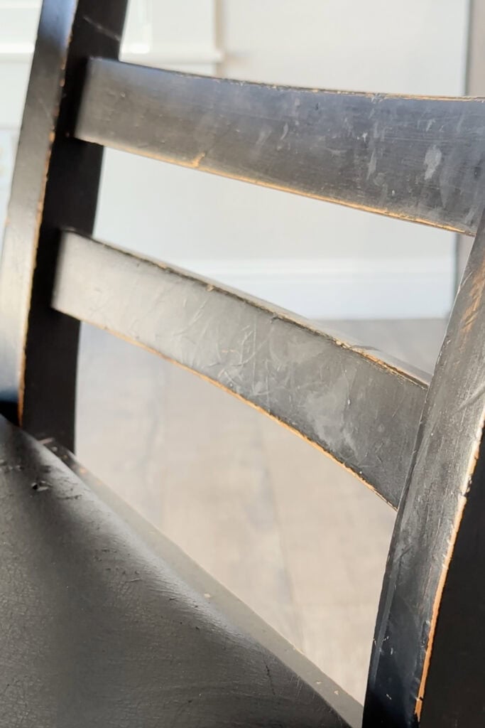 Closeup of a worn black wooden chair with scratches