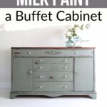 Distressed green buffet cabinet with white knobs, vase of flowers, and text: How to milk paint a buffet cabinet.