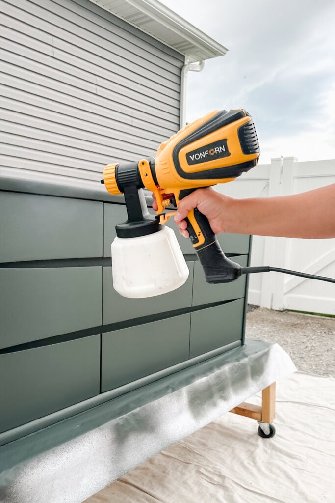 Using a Vonforn sprayer to paint a dresser outdoors
