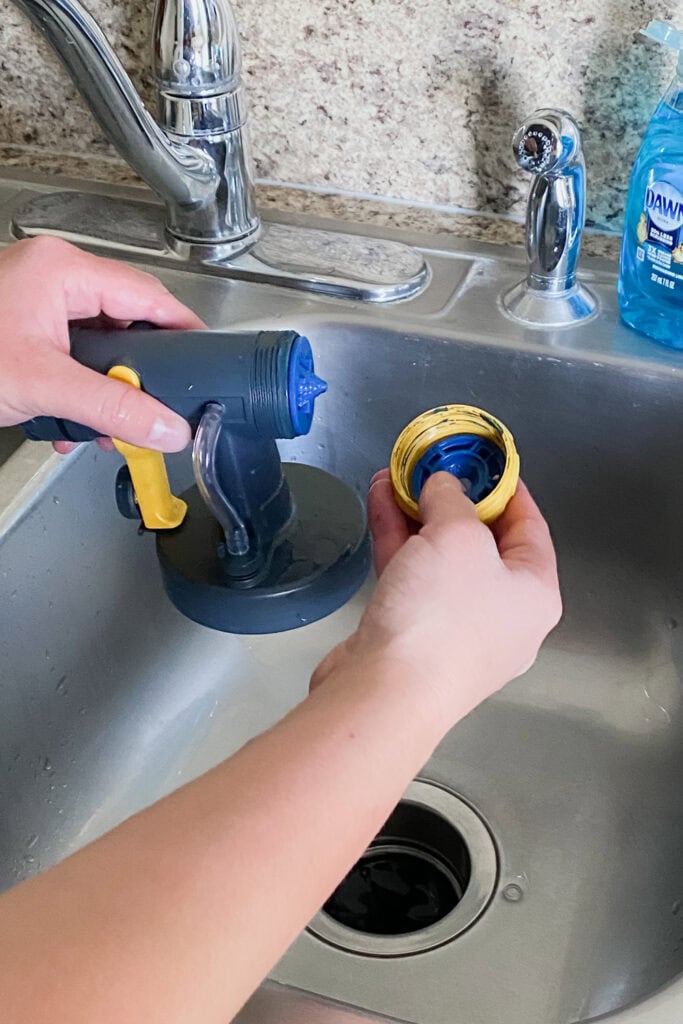 Hands holding sprayer parts by a kitchen sink