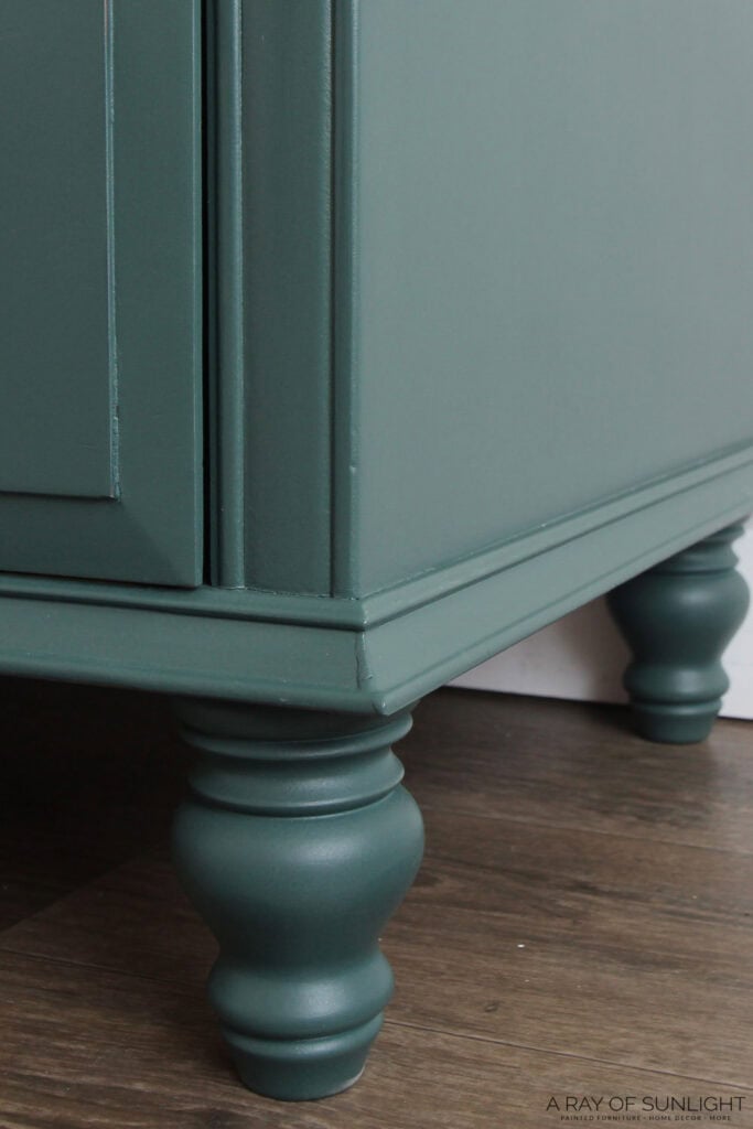 Closeup of a green painted wooden dresser with turned legs