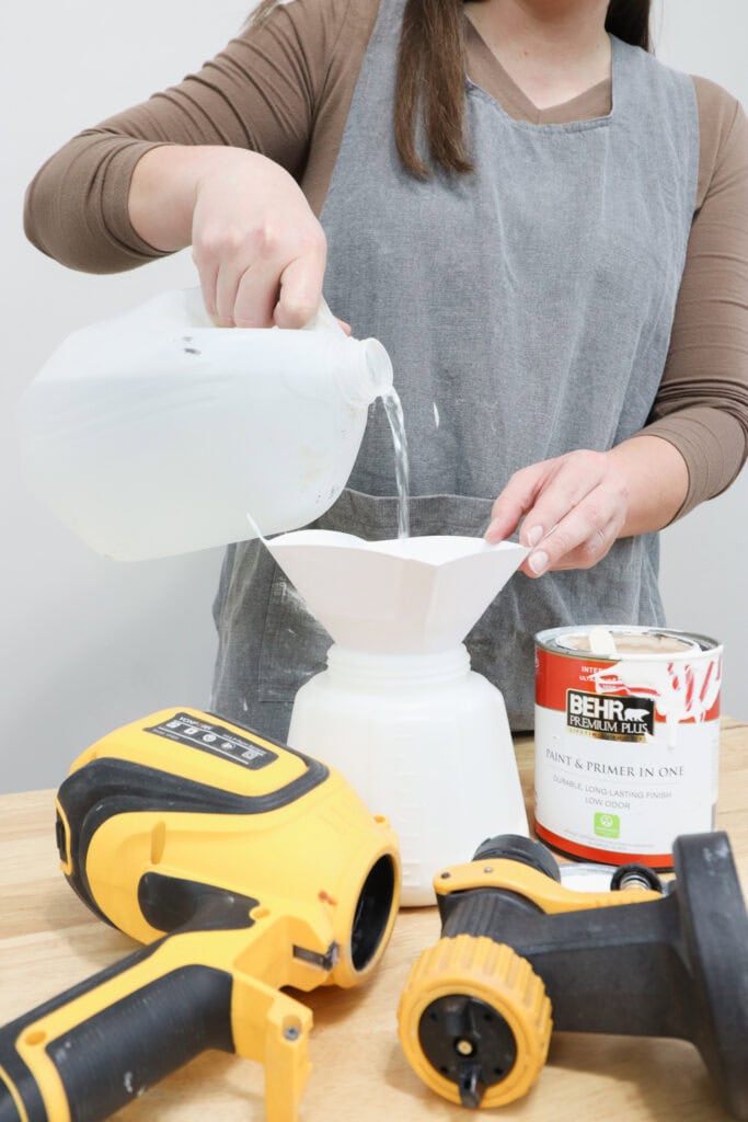 A person pours water into a sprayer container