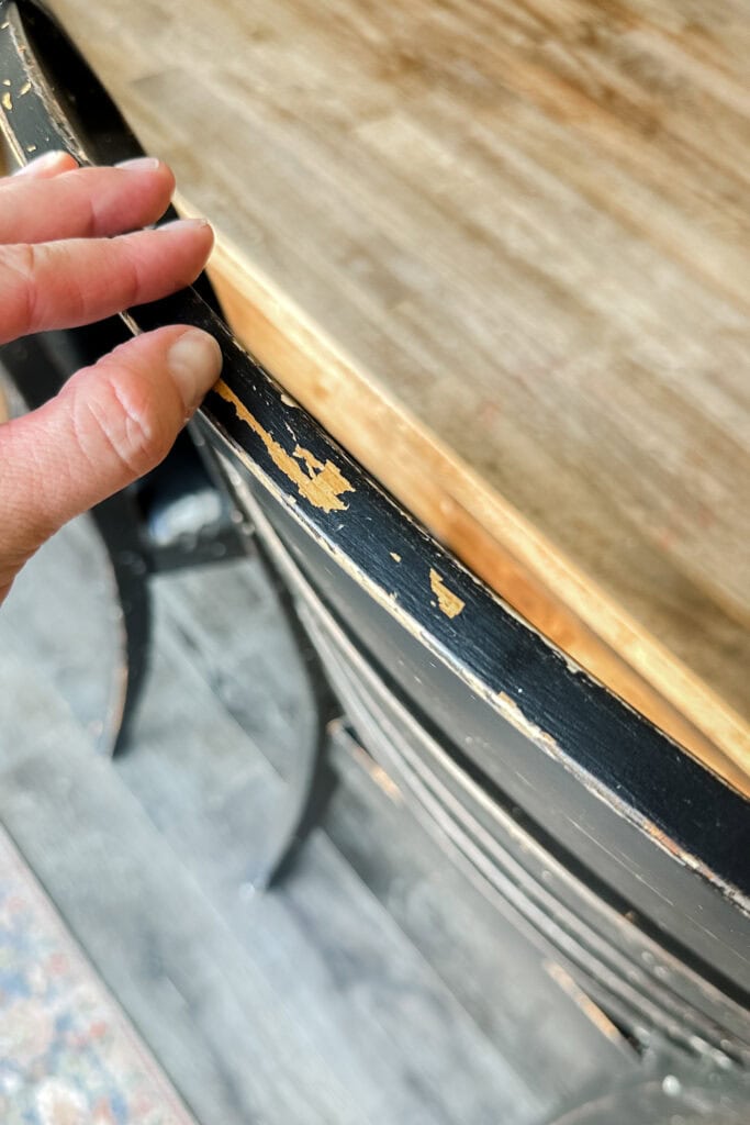 Hand touching a wooden chair with chipped paint