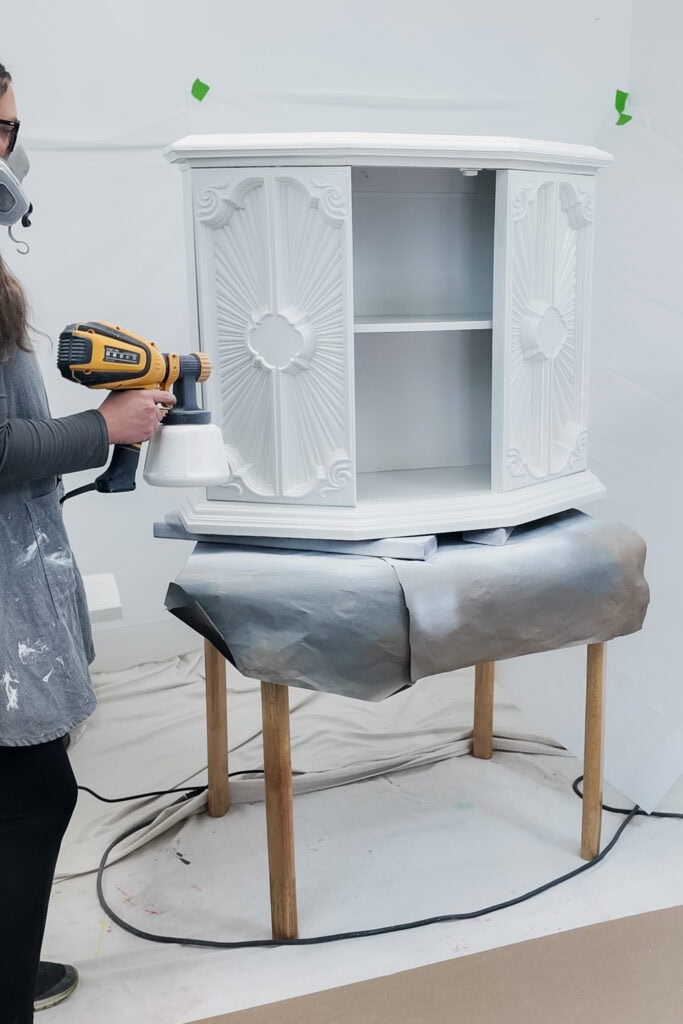 Spray painting a wooden cabinet placed on a table