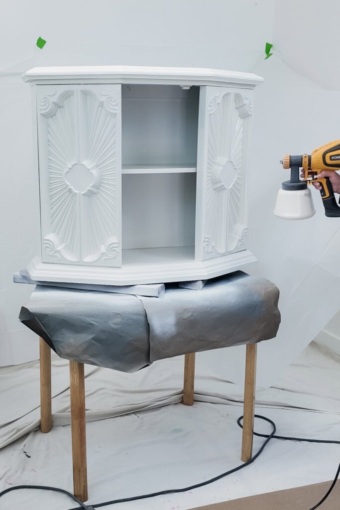 White ornate cabinet being spray painted on a table