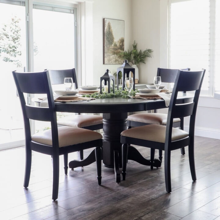 A round dining table set for four with black chairs