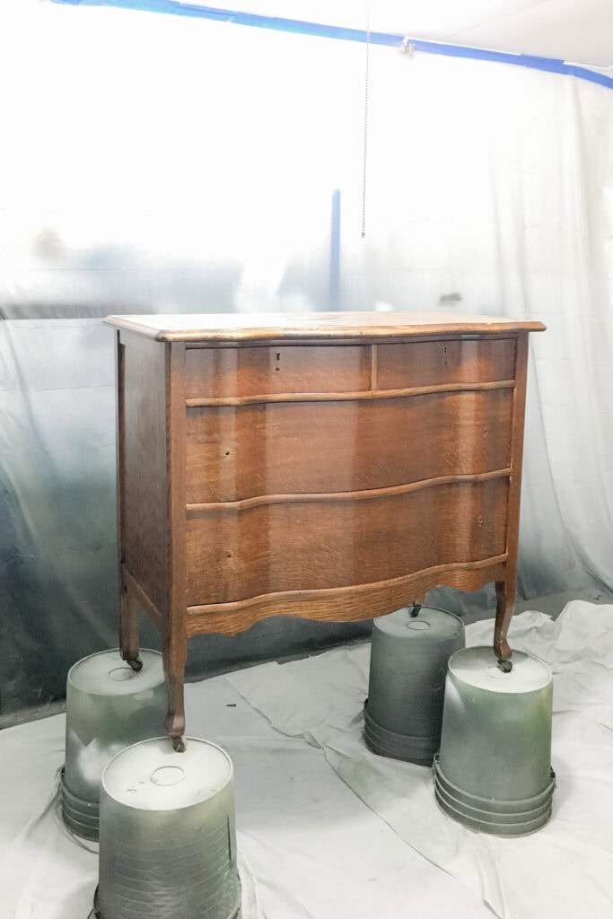A wooden dresser stands on overturned buckets in a room