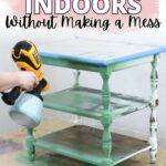 Person using a paint sprayer to paint a green three-tier table indoors, with protective coverings underneath.