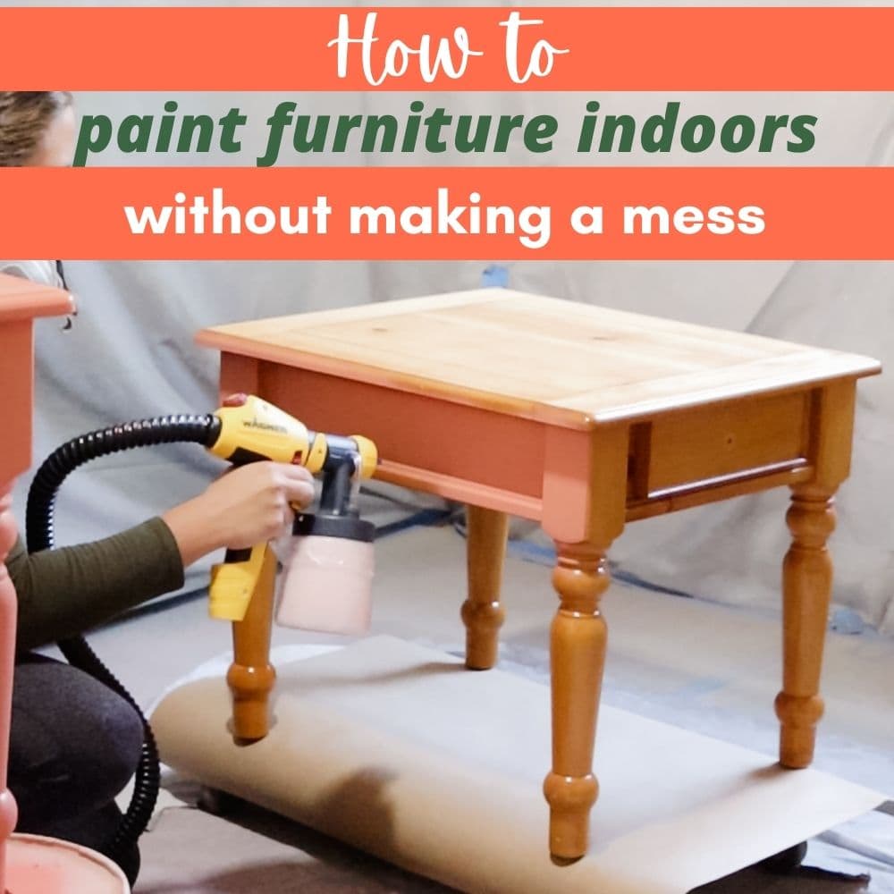 Using a paint sprayer on a wooden table, with protective sheets covering the floor and wall.