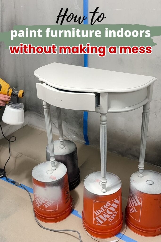 Spray painting a small gray table raised on four orange buckets