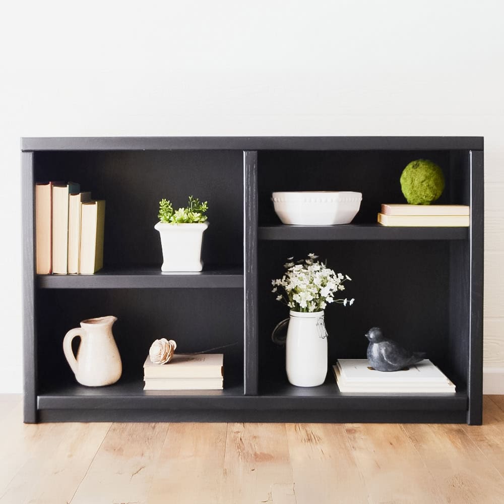 Black bookshelf with books, potted plants, and decorative items