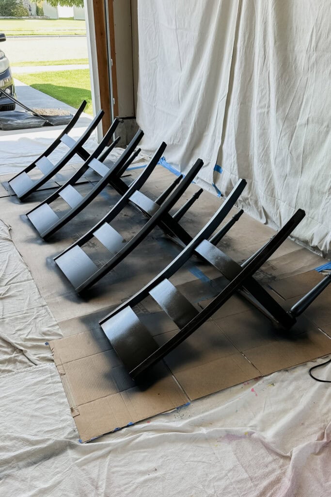 Four black wooden chairs in open garage