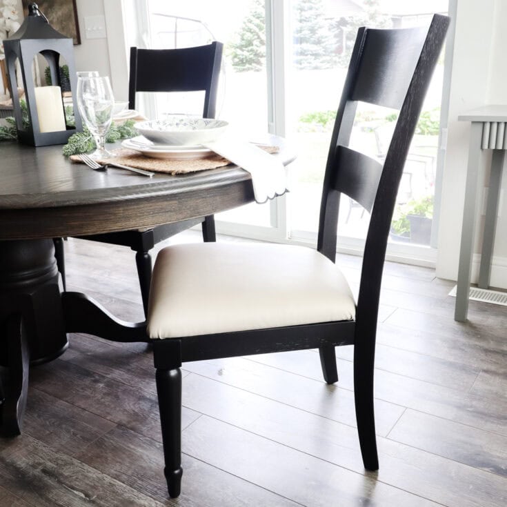 A black wooden chair with a cream cushion