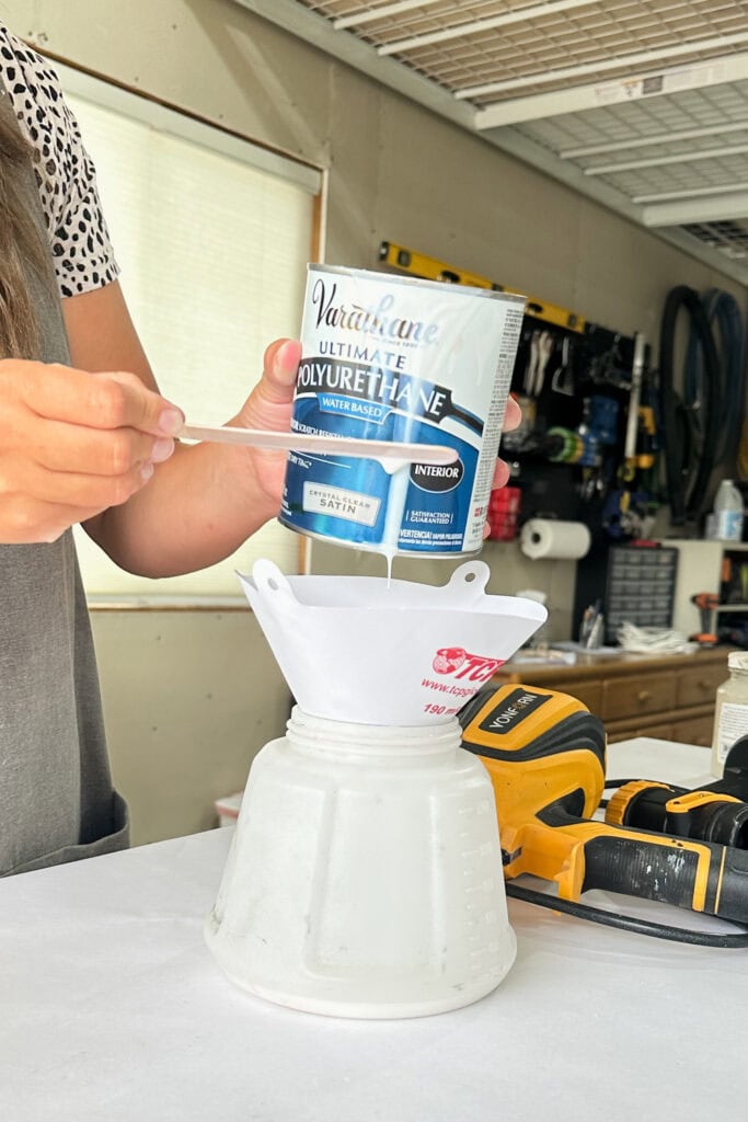 Person pouring Varathane polyurethane through a filter into a sprayer container.