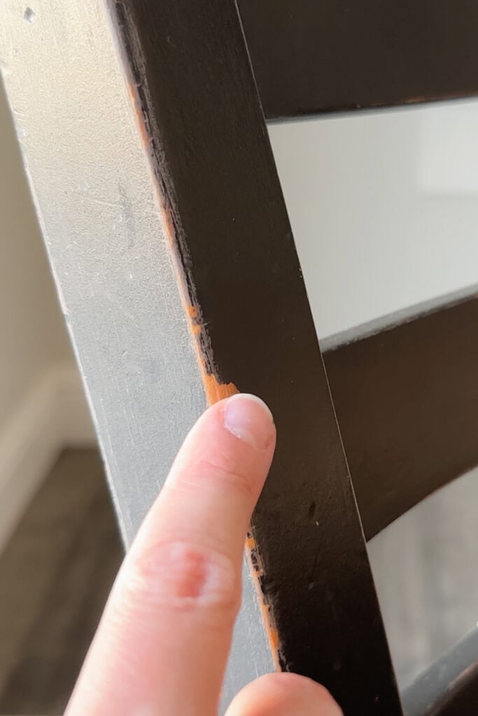 Scratched paint on the edge of a black wooden chair.