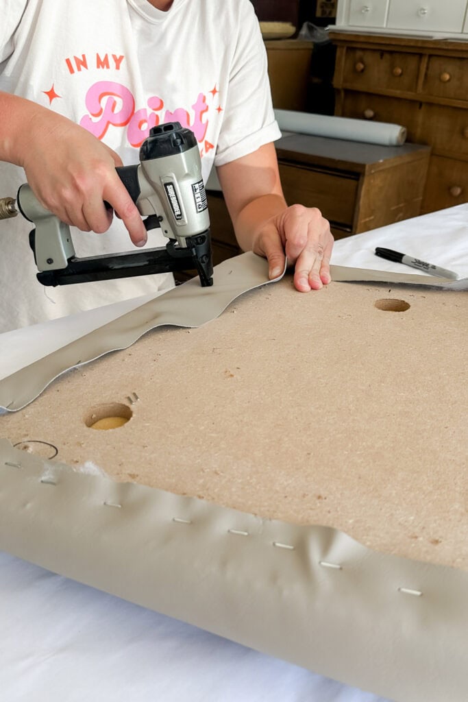 Person using a staple gun to attach leather to chair seat