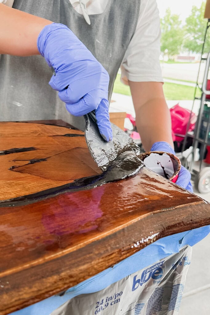Person in gloves scraping old finish from wooden top