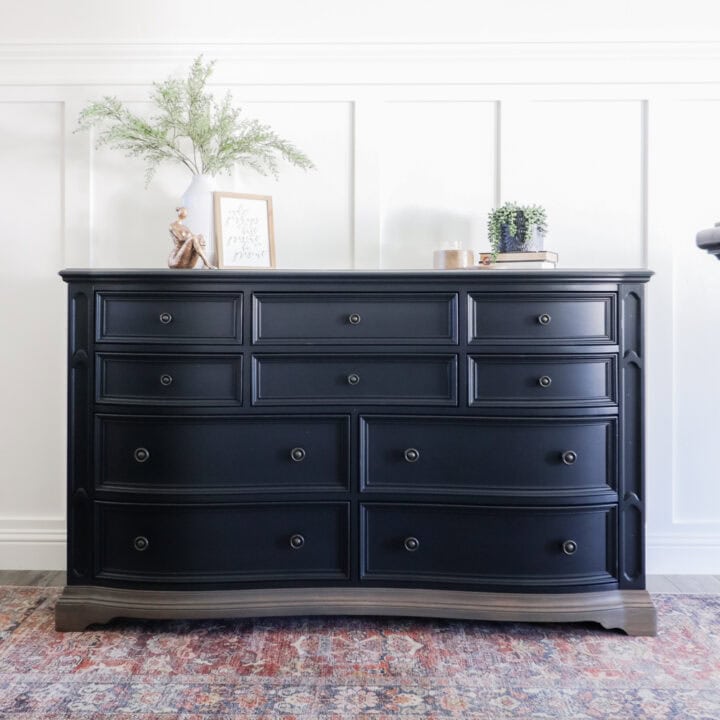 A black dresser with decor and plants on top