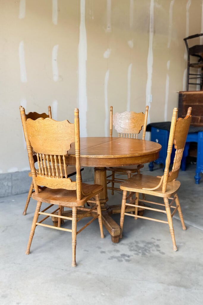 A round wooden dining table with four matching chairs in a garage