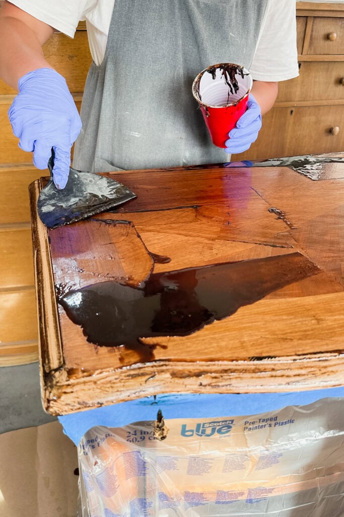 Person removing chemical stripper residue from wood top