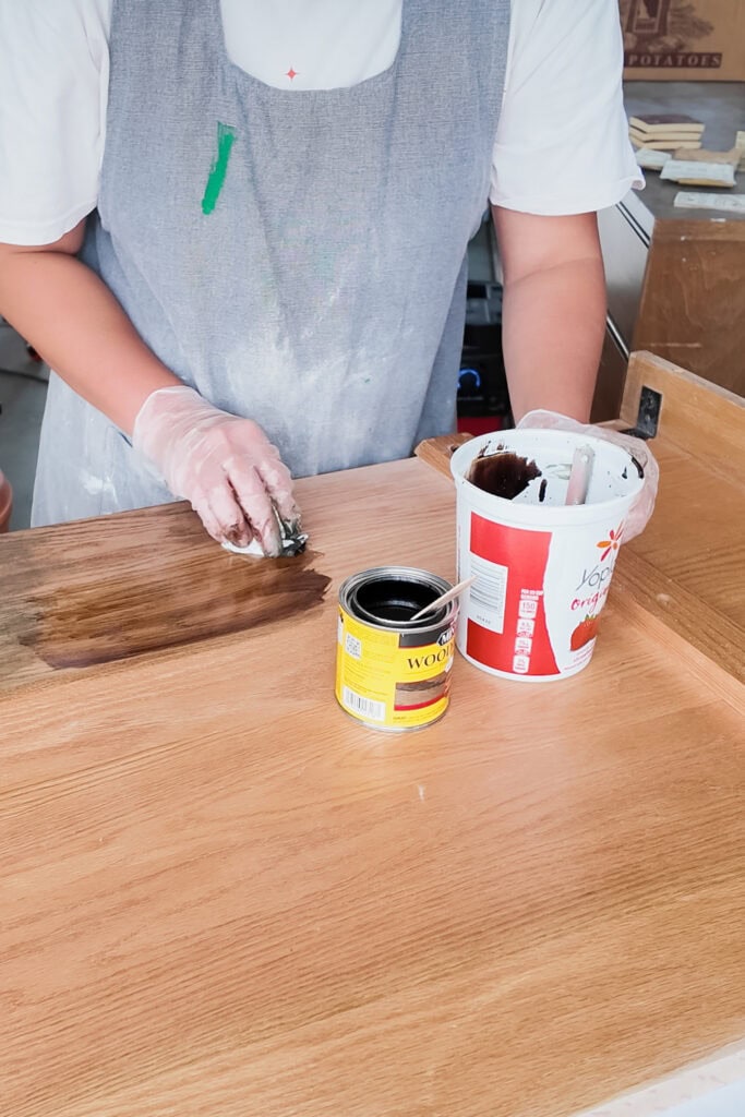 Person testing stain on wood