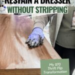 A person with a gloved hand stains a wooden top
