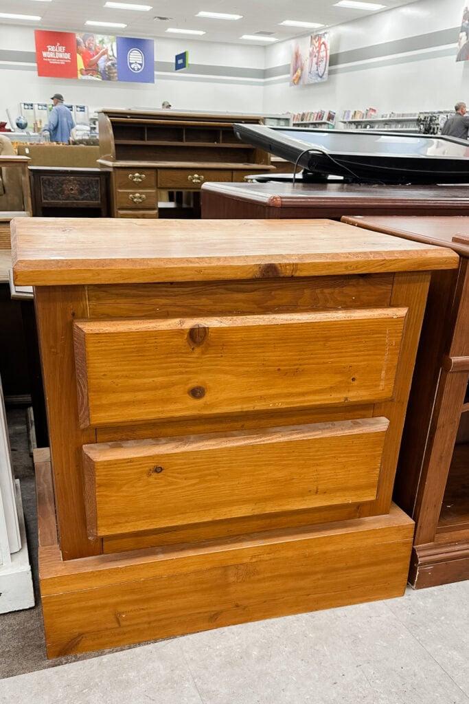 Wooden nightstand with two drawers on display in a furniture store.