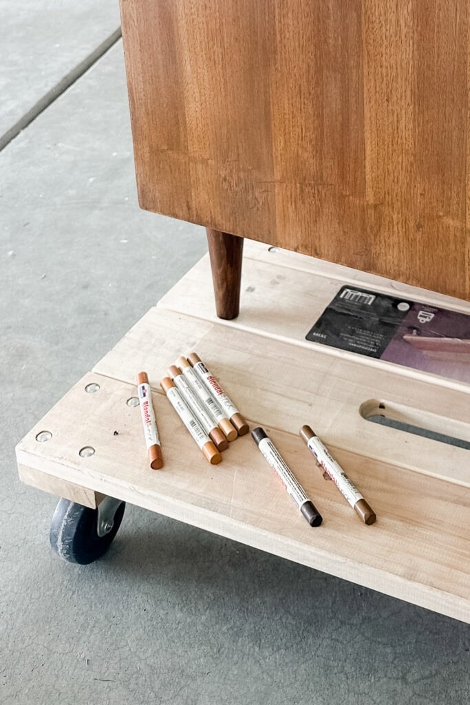 Several wood stain sticks lie on a wooden dolly