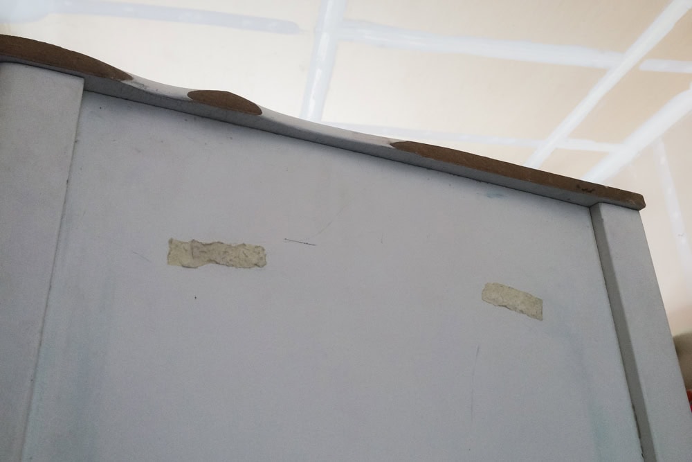 A white dresser with sticky tape on its side