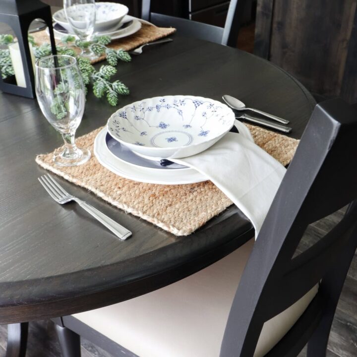 Dark stained round table with plates and cutlery on top