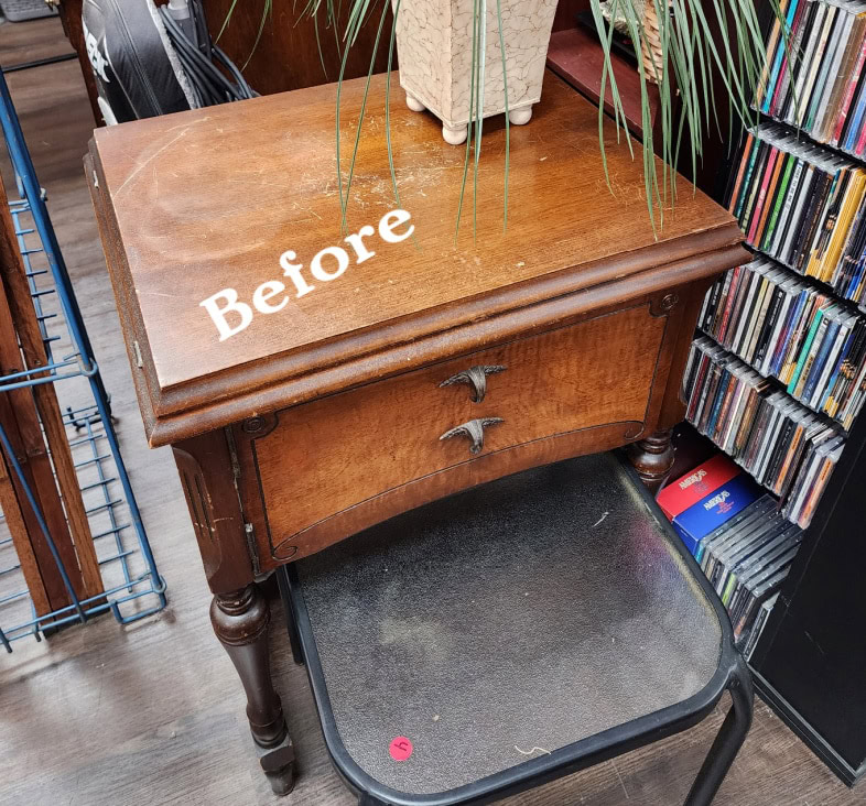 A worn wooden side table with Before written on top