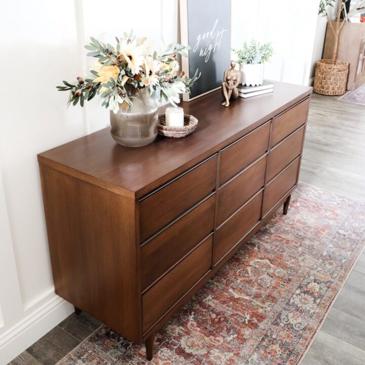 Refinished Midcentury wooden dresser with decor, flowers, and candles on top