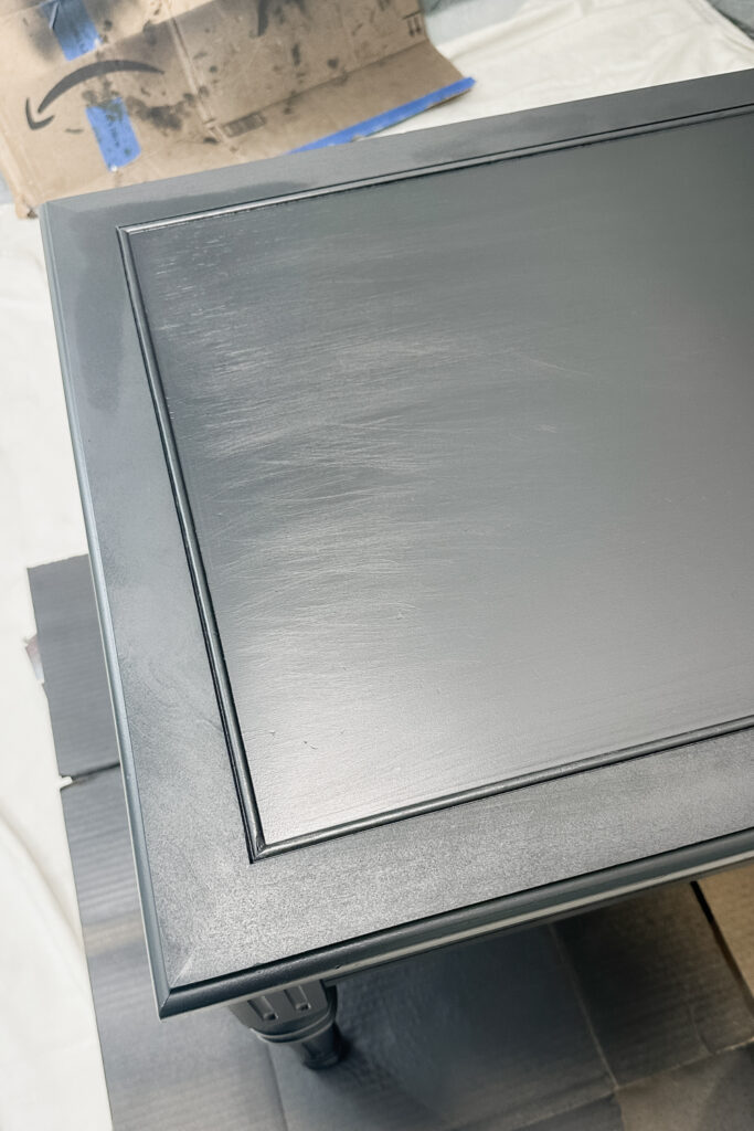 A close-up of a freshly painted black table with a raised rectangular border on the tabletop.