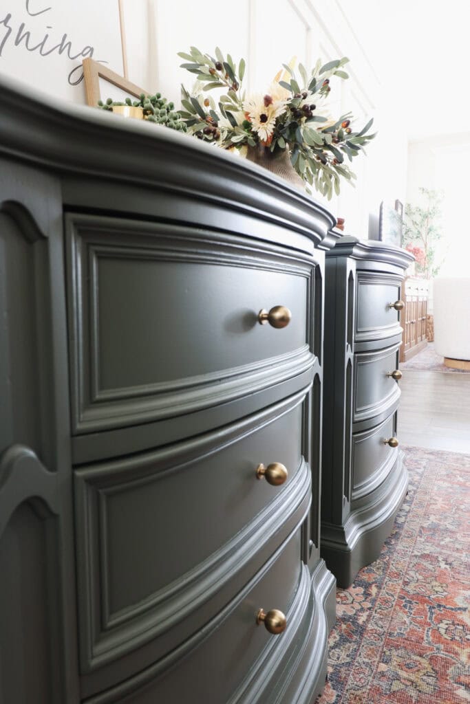 Close up of green curved dressers with gold round knobs