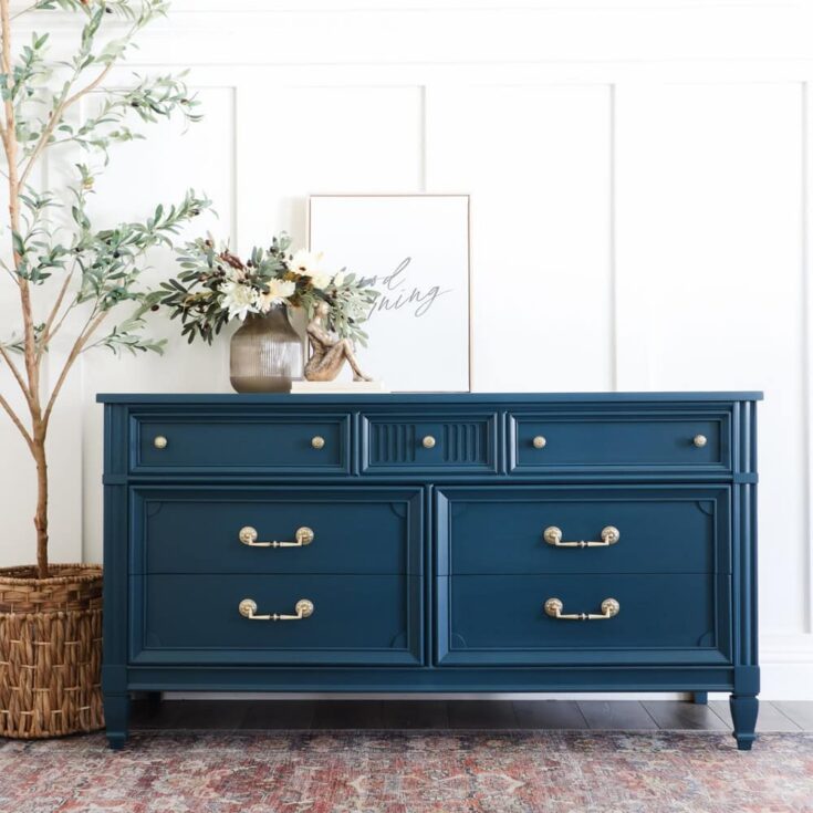 Blue dresser with gold handles, floral decor, and framed art