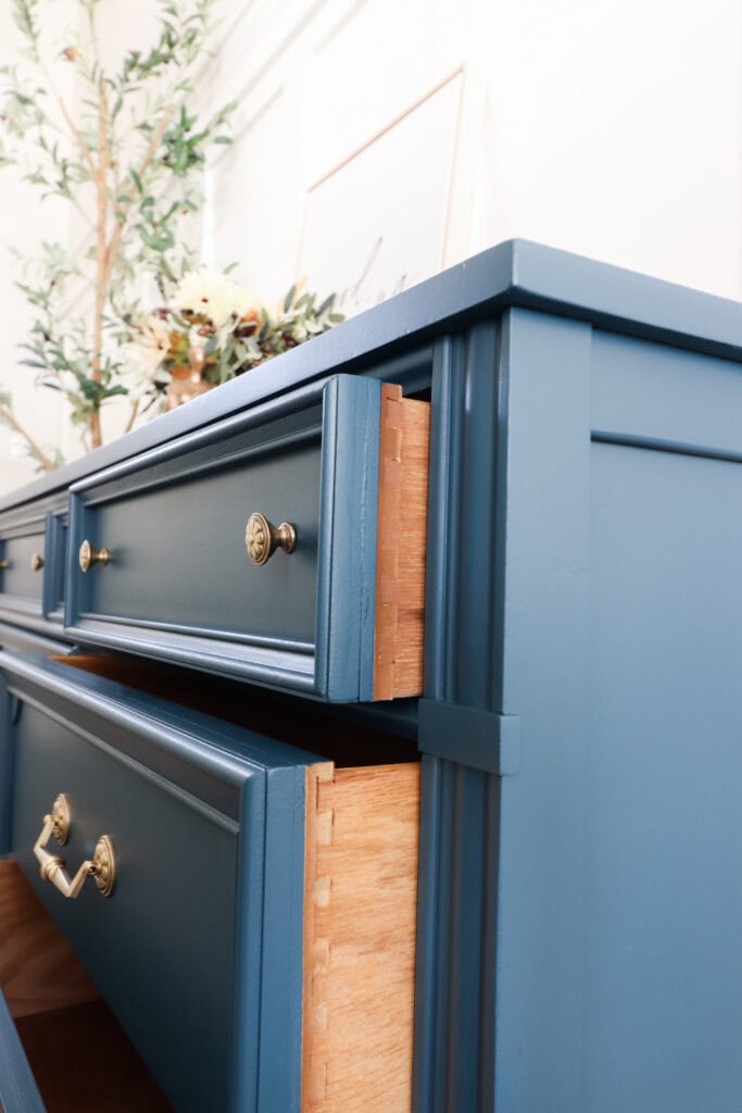 Close up of a blue dresser with gold handles, two drawers partially open