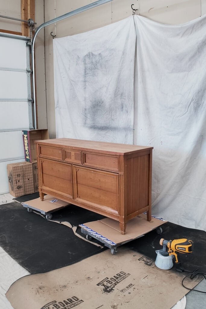 A wooden dresser in a painting setup in a garage