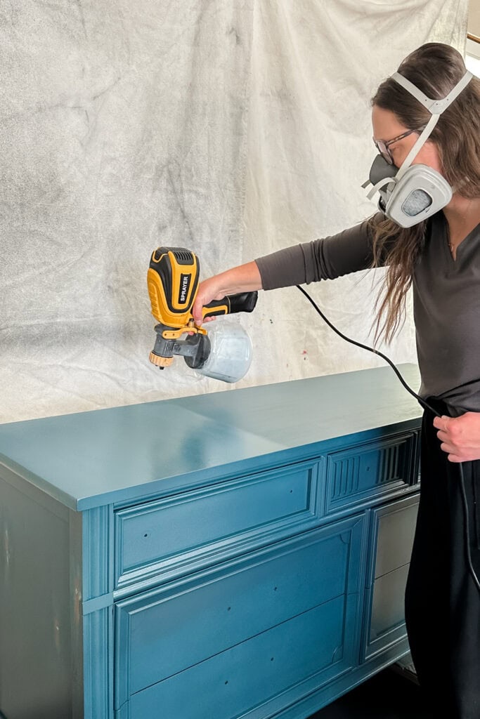 Natalie applying another coat of blue paint on dresser top