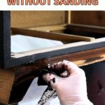 A gloved hand applies gel stain to wood on furniture with a cloth