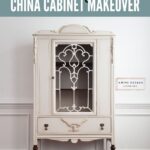 Cream colored vintage china cabinet with ornate details, glass door, and dark wood legs