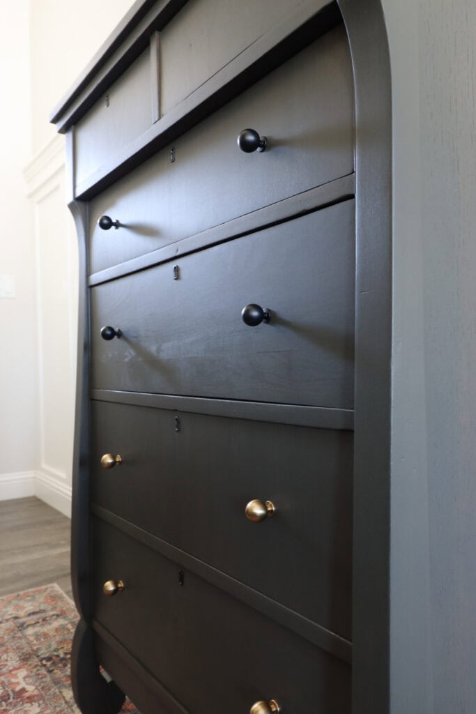 Closeup of stained dresser with black and gold knobs on its drawers.