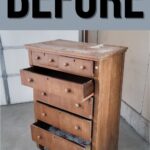 Old wooden dresser with damaged drawers, labeled BEFORE, standing in a garage or workshop.